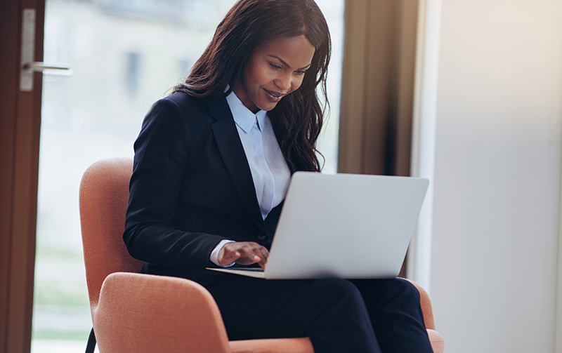 Smiling African American businesswoman working on a laptop - JN Bank Young Professionals Overseas Want to Invest in Jamaica