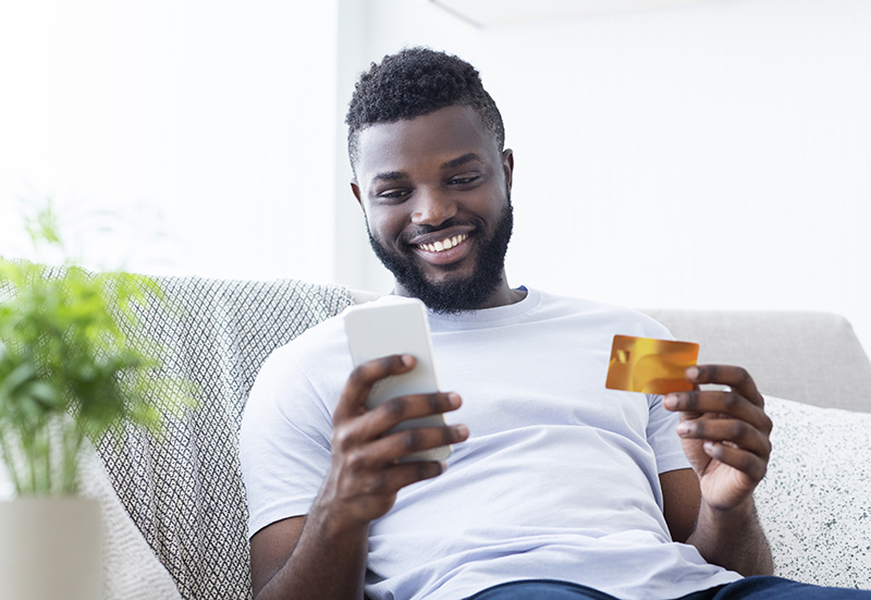 African american man holding credit card and cellphone - JN Bank