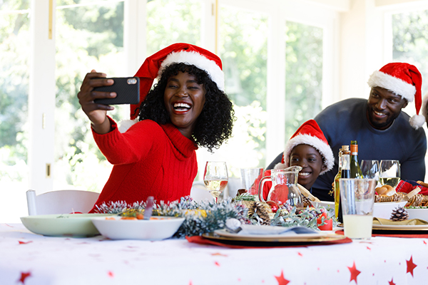 Multi generation african american family taking a selfie with smartphone, smiling and wearing santa hats. quality family time christmas celebration. - JN Bank