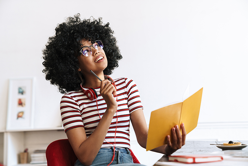 Pleased african american student girl thinking and doing homewor - JN Bank